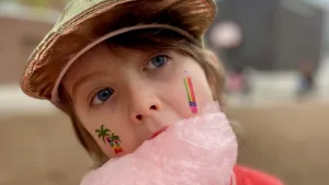 Brock student with colorful temporary tattoos eating cotton candy