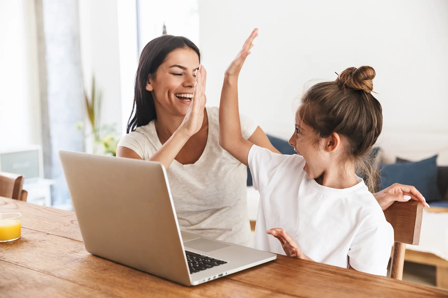 Woman and child high-fiving in front of a laptop